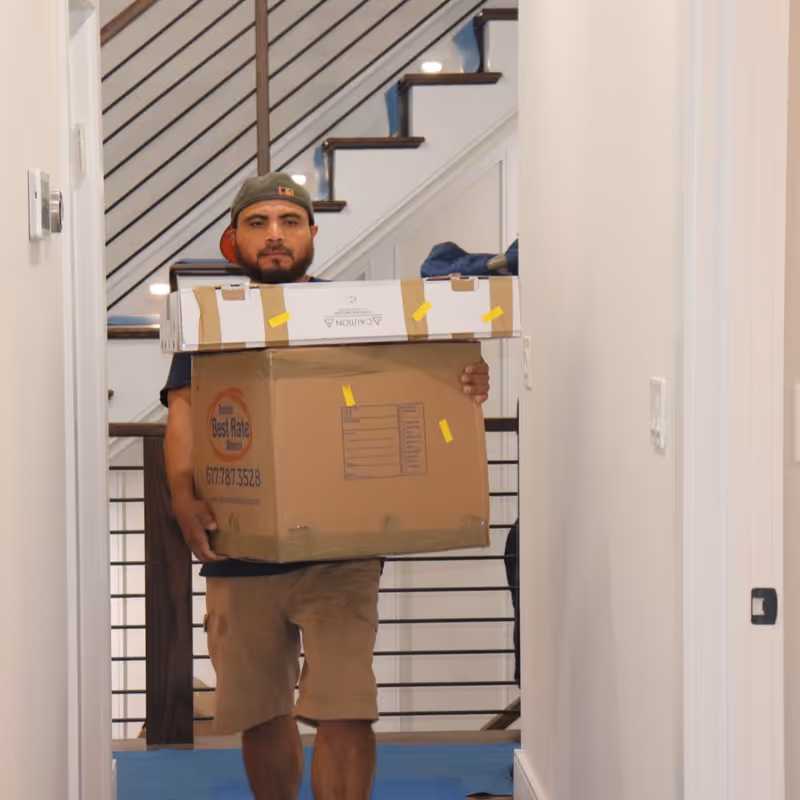 Boston Best Rate Movers crew member carrying boxes through a hallway