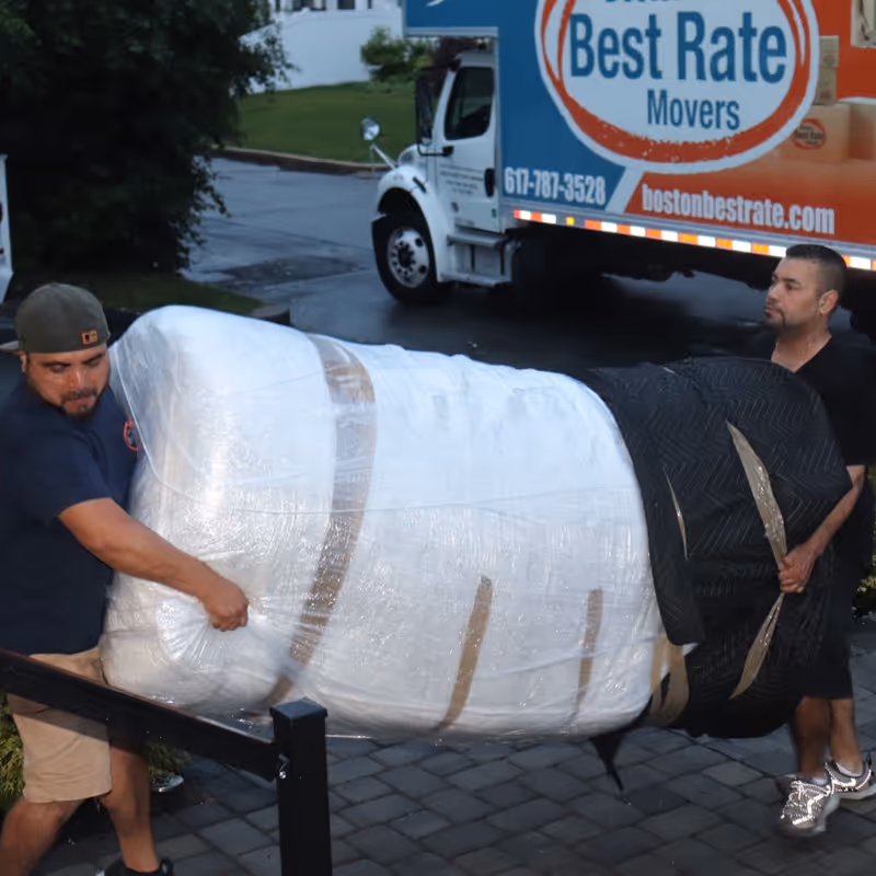 Boston Best Rate Movers crew carrying wrapped furniture to the home