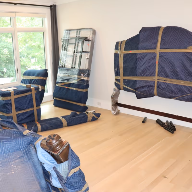 Living room furniture fully wrapped in moving blankets ready for transport