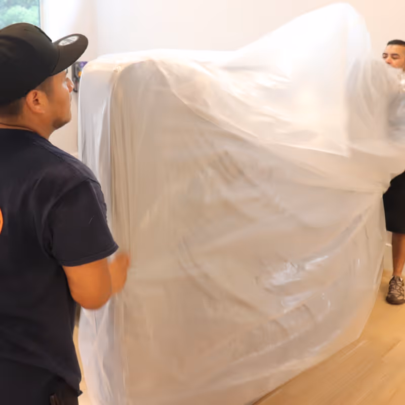 Two Boston Best Rate Movers crew members wrapping a mattress for protection