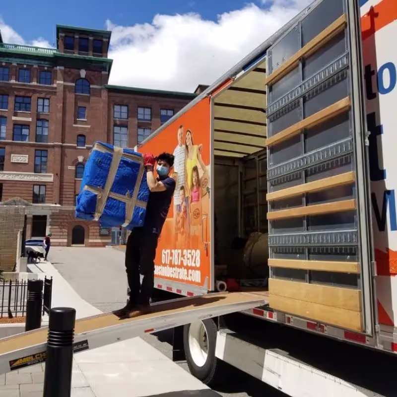 Professional movers wrapping large furniture piece in Boston